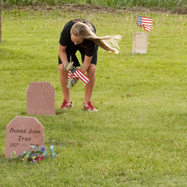 A young girl places a flag at a grave for Memorial Day 2010